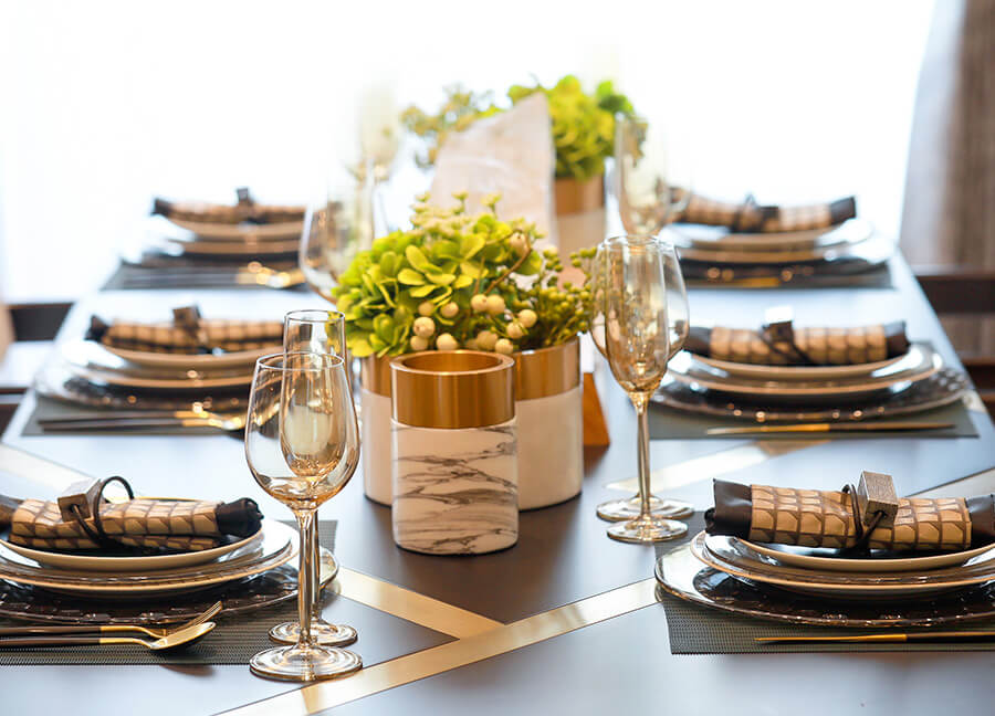 Formal set dining room table set with low succulent centerpieces and wine glasses.