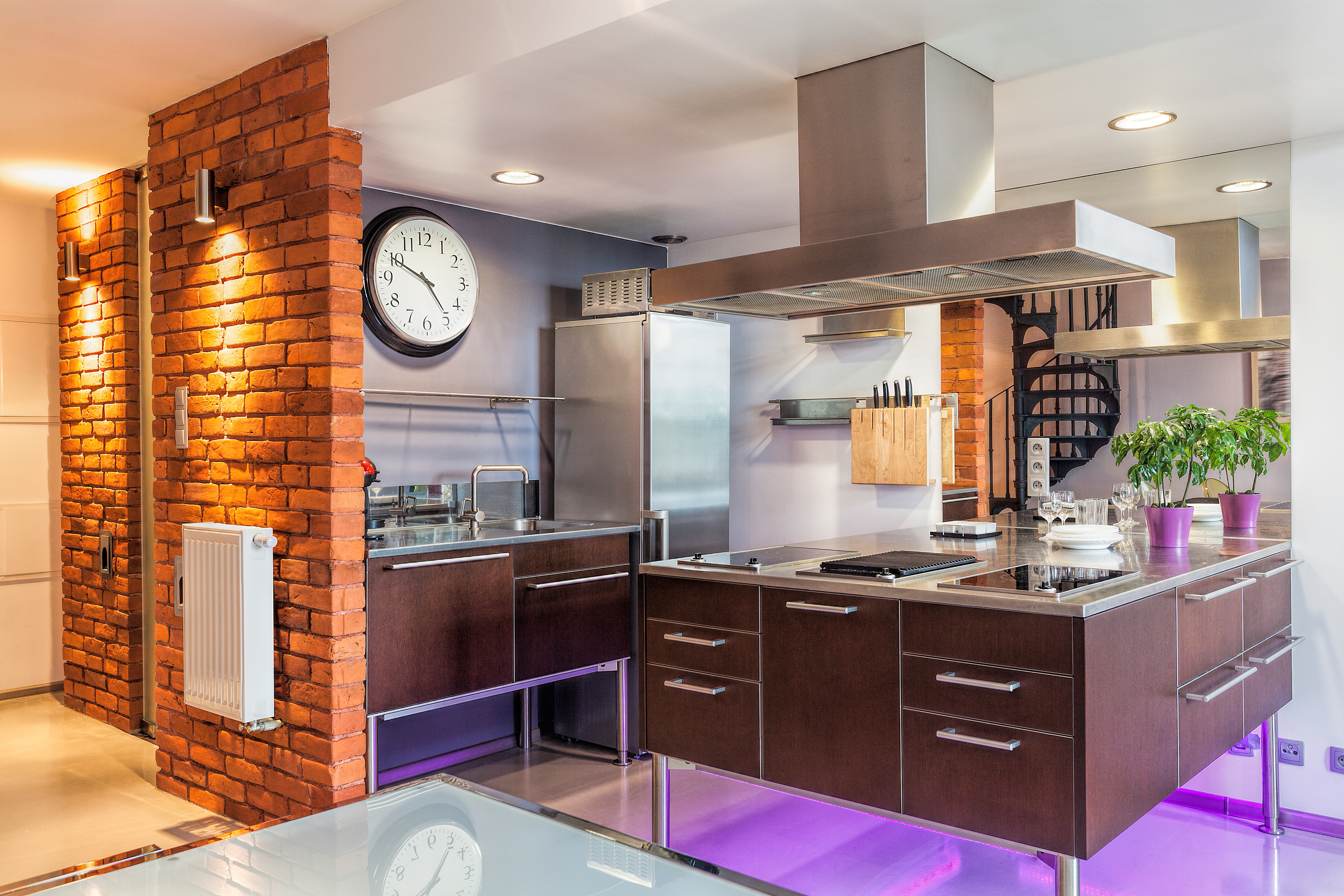 Modern kitchen featuring exposed brick and heavy use of stainless steel appliances and fixtures.