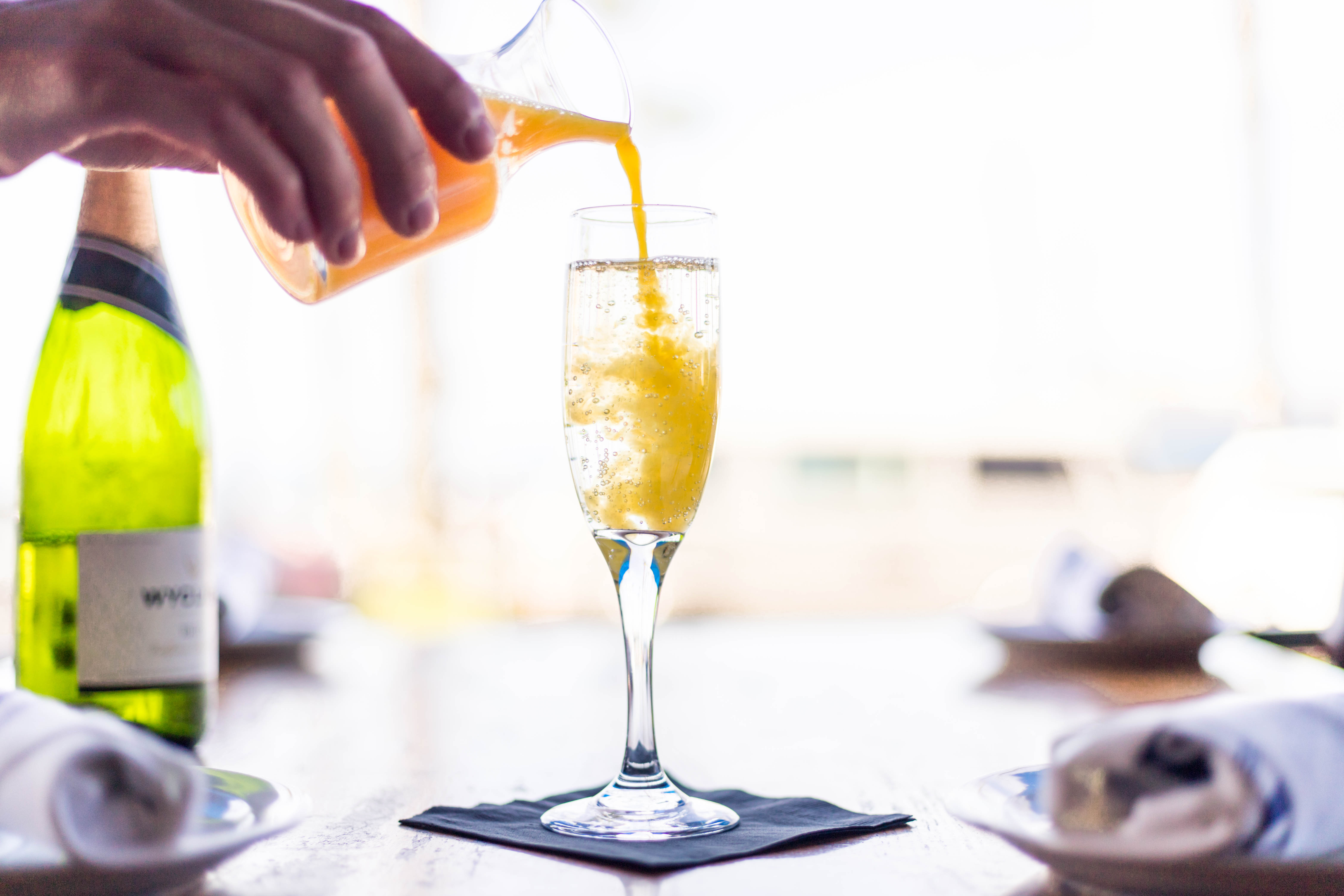 orange juice being poured in champagne glass