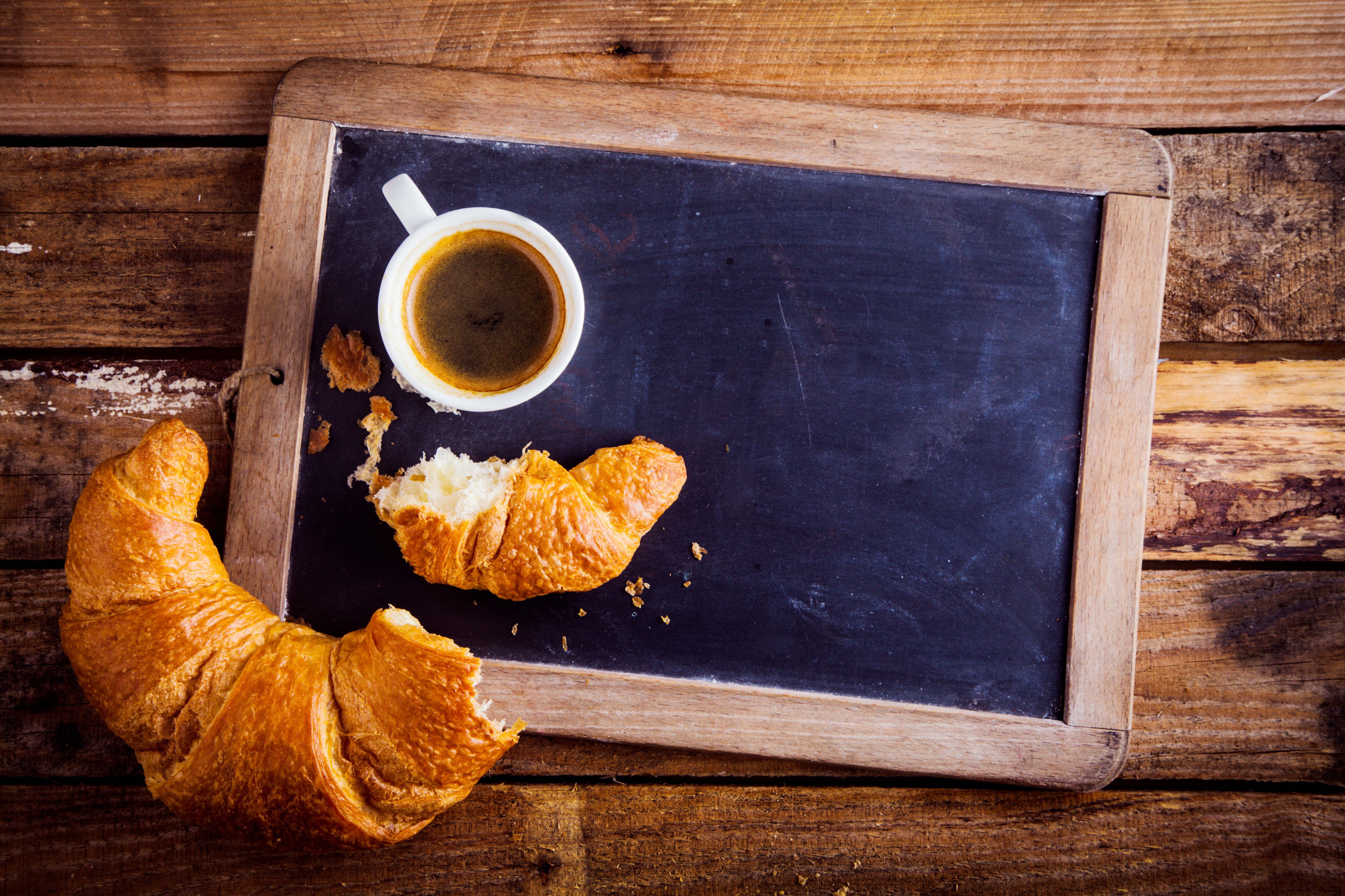 chalk board menu on table with coffee and croissant 