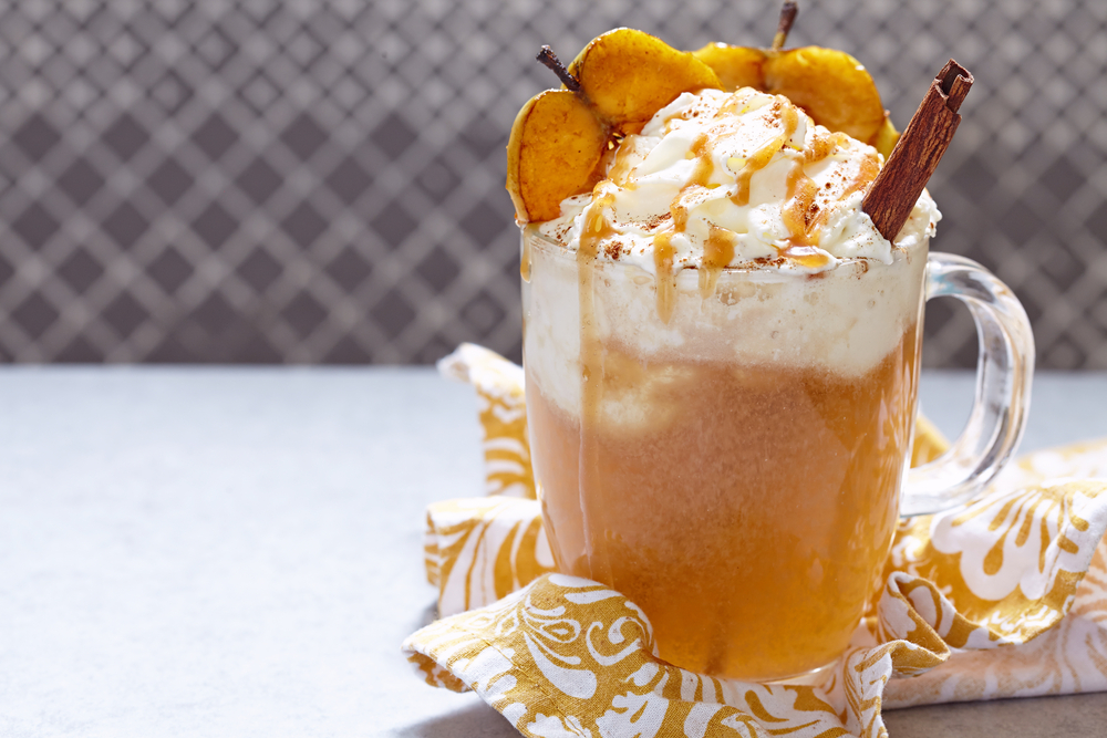 warm vanilla cider in a glass mug with whipped cream on top